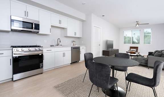 a kitchen and living room with white cabinets and a table and chairs