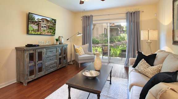 A living room with a couch, a coffee table, and a painting on the wall at The Legacy Apartments in Seminole Heights, FL