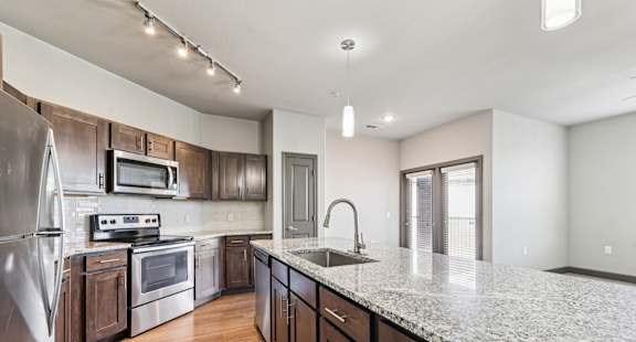 A kitchen with a granite countertop and stainless steel appliances.at North Creek, Hutto, TX, 78634