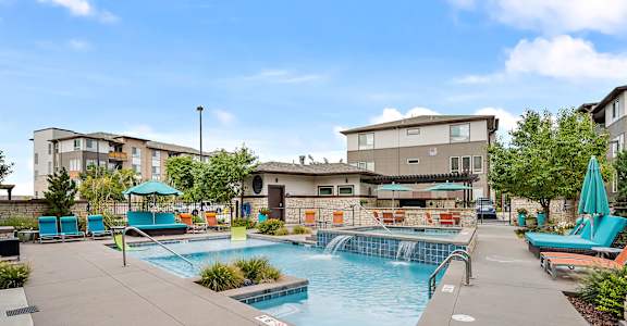 A swimming pool with a waterfall and a building in the background.