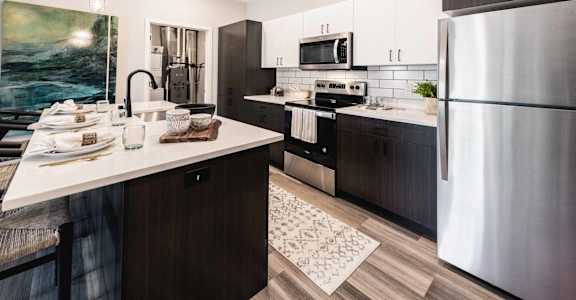 A modern kitchen with a refrigerator, sink, and dining table.