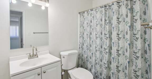 A white bathroom with a floral shower curtain.