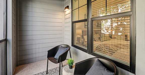 A chair sits on a porch with a potted plant on the table at The Stadler Luxury Apartments, Bradenton, FL 34210