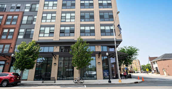A modern building with a glass facade is situated on a street corner at Crossroads 389 Apartments, New Jersey, 07601