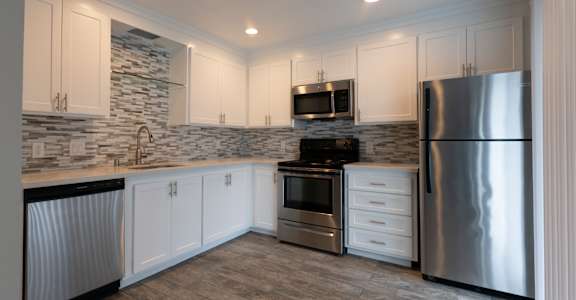 a kitchen with white cabinets and stainless steel appliances