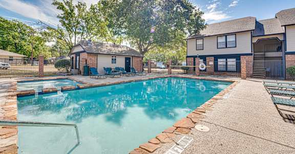 A swimming pool surrounded by a concrete patio and a black fence.