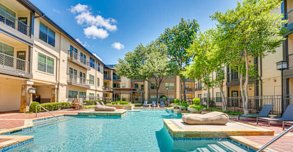 A swimming pool in a residential area surrounded by trees and buildings.