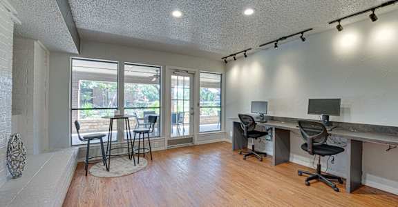 A room with a desk and chairs in front of a window.