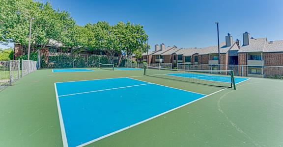 A tennis court with a blue surface and a green fence.