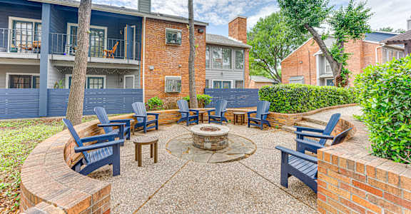 A patio with a fire pit and chairs.