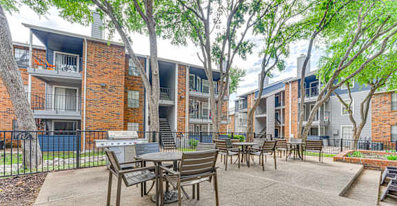 A patio with a table and chairs is surrounded by apartment buildings.