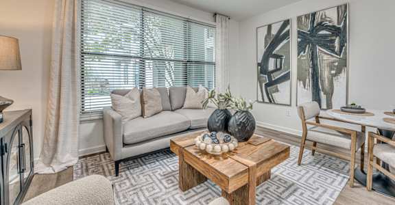 A living room with a grey couch, a wooden coffee table, and a painting on the wall.