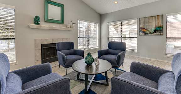 A living room with grey chairs and a green vase on the coffee table.