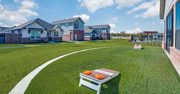 A white picnic table with oranges on it sits in the middle of a grassy area.