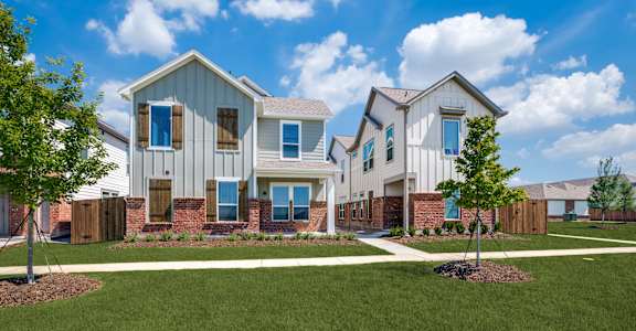 A row of houses with a green lawn in front.