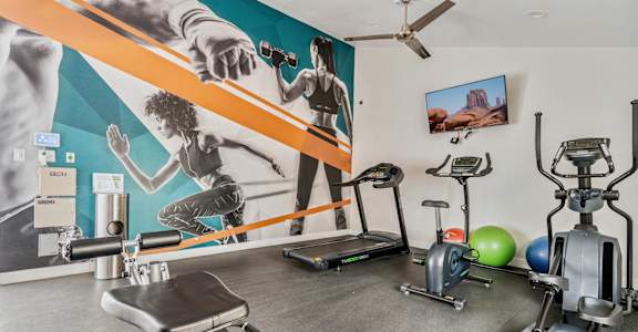 a gym with cardio equipment and a large mural on the wall