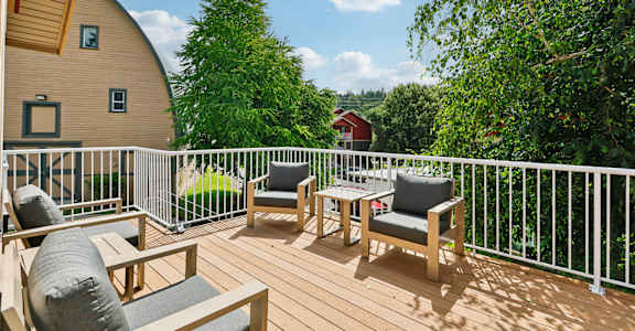 A wooden deck with two chairs and a table  at THE TIMBERS BY VINTAGE, Arlington