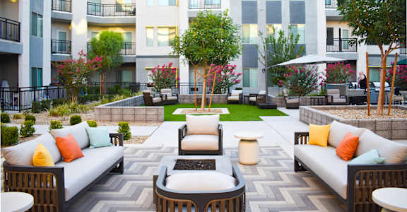 A patio with a couch, chairs, and a table in front of a building.