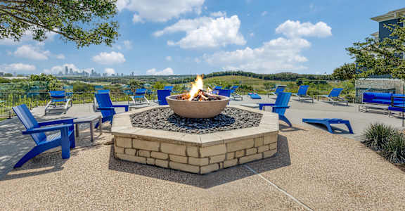 a fire pit with blue chairs and a view of the city