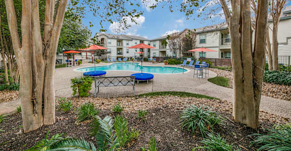our apartments offer a community pool with tables and umbrellas at Sunrise Canyon, Universal City, TX, 78148