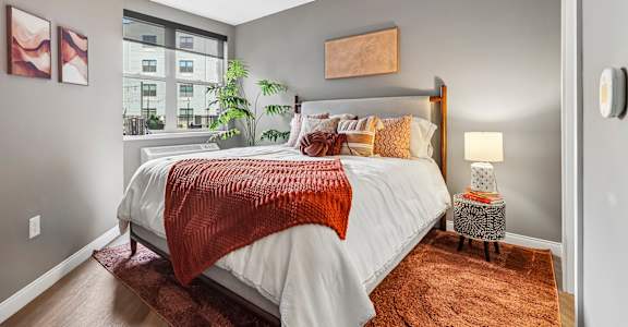 A bedroom with a large bed and a window overlooking a cityscape.