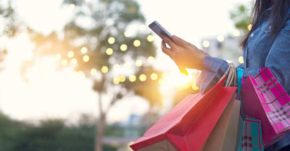 a woman holding shopping bags and looking at her cell phone at Sunset Heights, San Antonio, TX