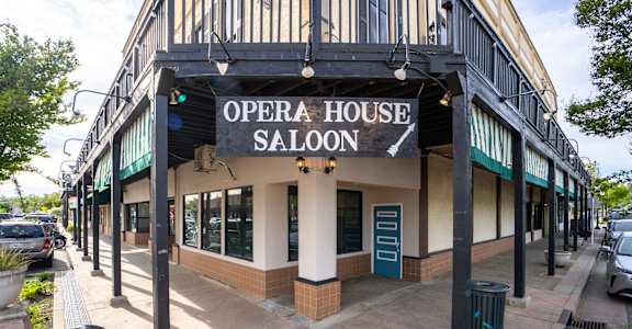 A white building with a black awning that says Opera House Saloon.