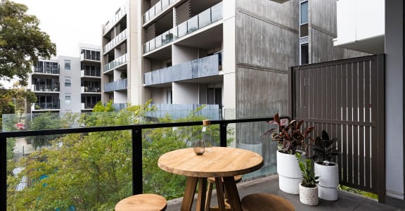 a balcony with a table and three stools in front of an apartment building