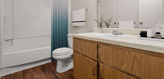 A white toilet sits in a bathroom with wooden cabinets.