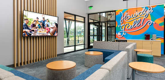 a lounge area with couches and tables and a large screen tv