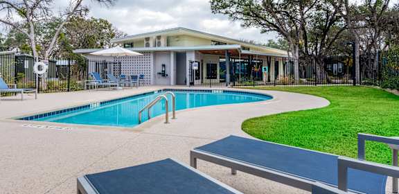 a swimming pool with benches and a building in the background