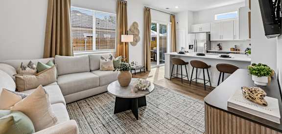 A modern living room with a white sofa, a coffee table, and a flat-screen TV mounted on the wall.