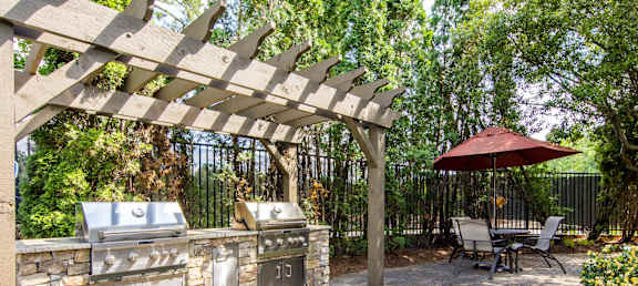an outdoor kitchen with stainless steel appliances and a wooden pergola