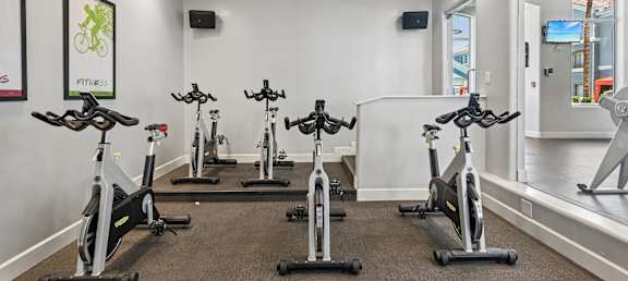 A room with a row of stationary bikes.