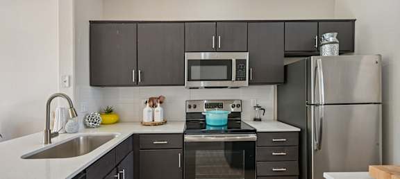 A modern kitchen with dark brown cabinets and stainless steel appliances.