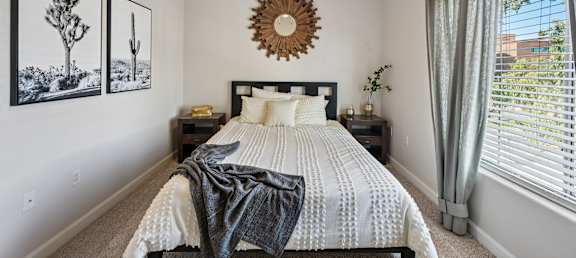 A bedroom with a bed, nightstand, and two framed pictures on the wall.