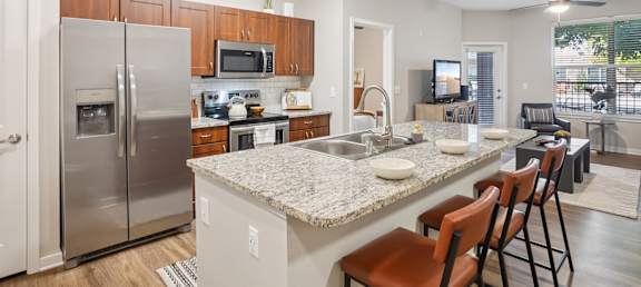 A kitchen with a refrigerator, microwave, and sink.