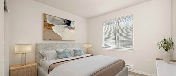 A bedroom with a large bed and a painting on the wall.