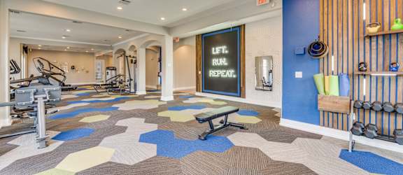 a gym with weights and cardio machines and a chalkboard on the wall