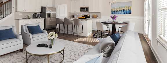 a living and kitchen area with a ceiling fan and couches