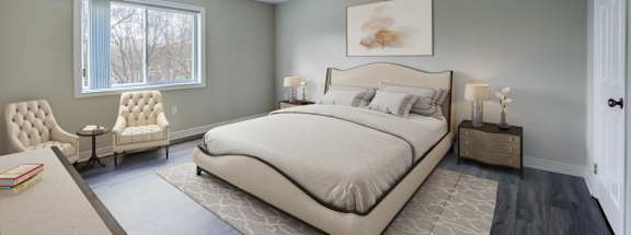 a bedroom with a bed and two chairs in a 555 waverly unit