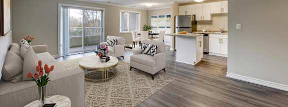 a living room with couches and chairs and a kitchen in the background
