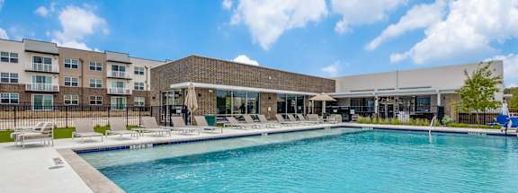 A large swimming pool in front of a building with a sunny sky.