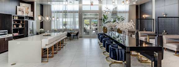 A modern kitchen with a long white island and bar stools.