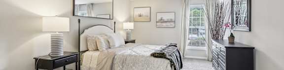 A bedroom with a bed, nightstand, and a window with a view.