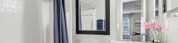 A white bathroom with a toilet, sink, and mirror.
