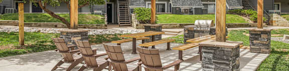A wooden pergola with chairs and a table is in the foreground of a residential area.