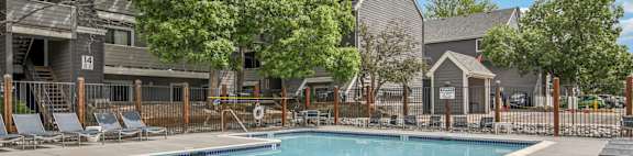 A swimming pool surrounded by lounge chairs and trees.