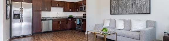 a living area with a couch coffee table and a kitchen with stainless steel appliances