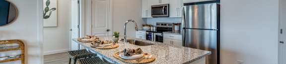 A kitchen with a granite countertop and stainless steel appliances.